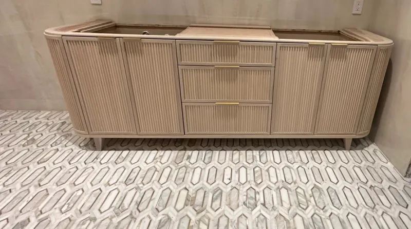 Curved fluted vanity. Vanity on feet with rounded ends, fluted doors and three drawers in the middle.
