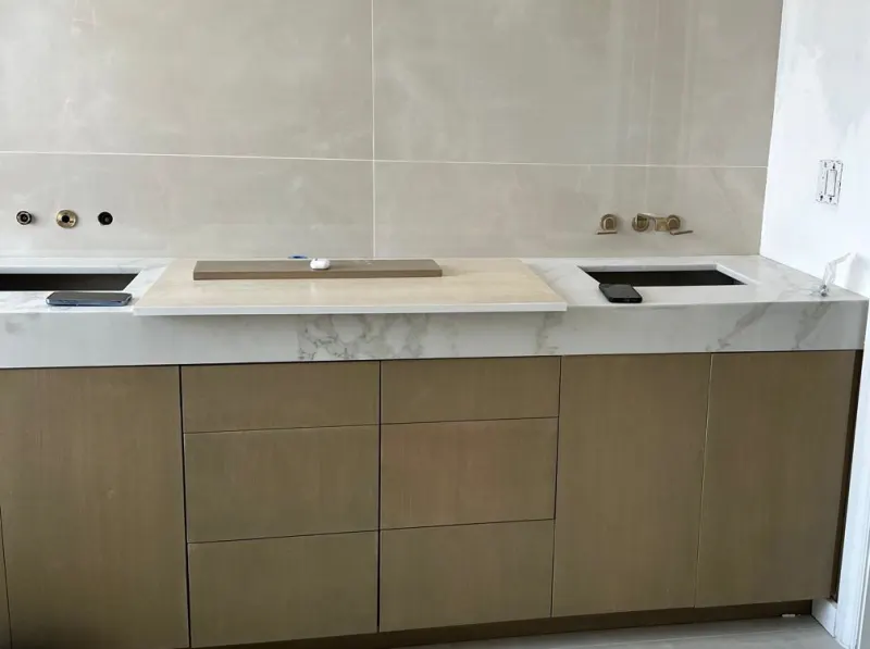 Double vanity with drawers. Wall-to-wall vanity for two sinks, with flat fronts and drawers in the middle.