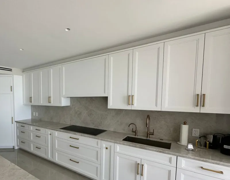 White shaker kitchen. White shaker doors on the upper and base cabinets, with drawers and a built-in hood cover.