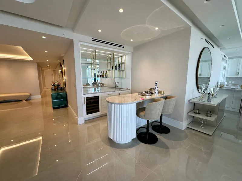 Bar with curved counter. Curved counter with a white fluted front, base cabinets and glass shelving on the back wall.