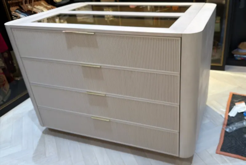 Closet island. Island with four fluted drawers, rounded corners and a glass top that shows what is inside.