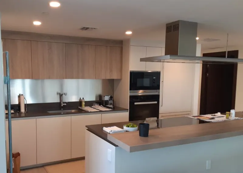 Two-tone kitchen. Wood-finish upper cabinets over white base cabinets, with a peninsula in the same white.